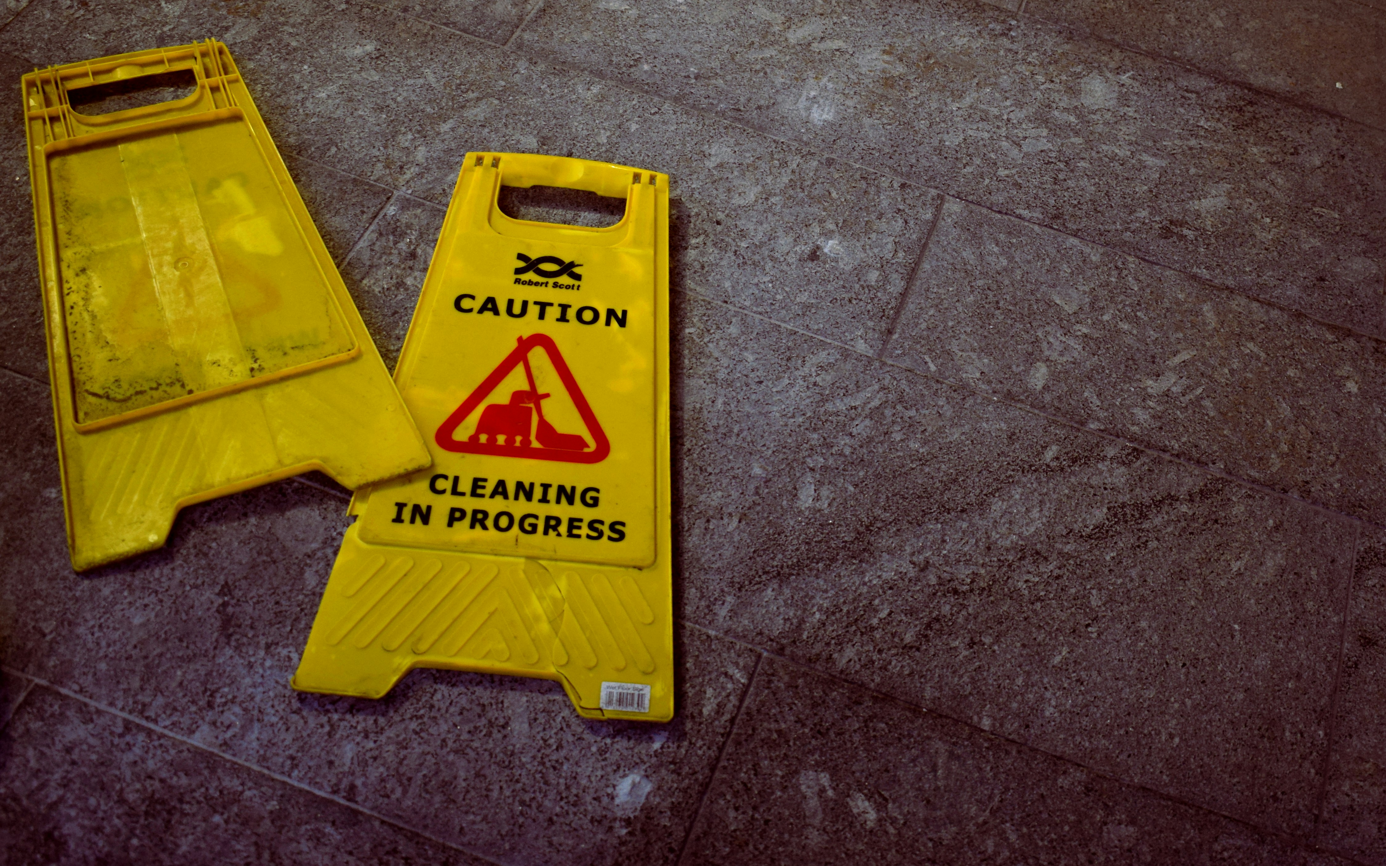 two sides of a caution cleaning in progress sign.