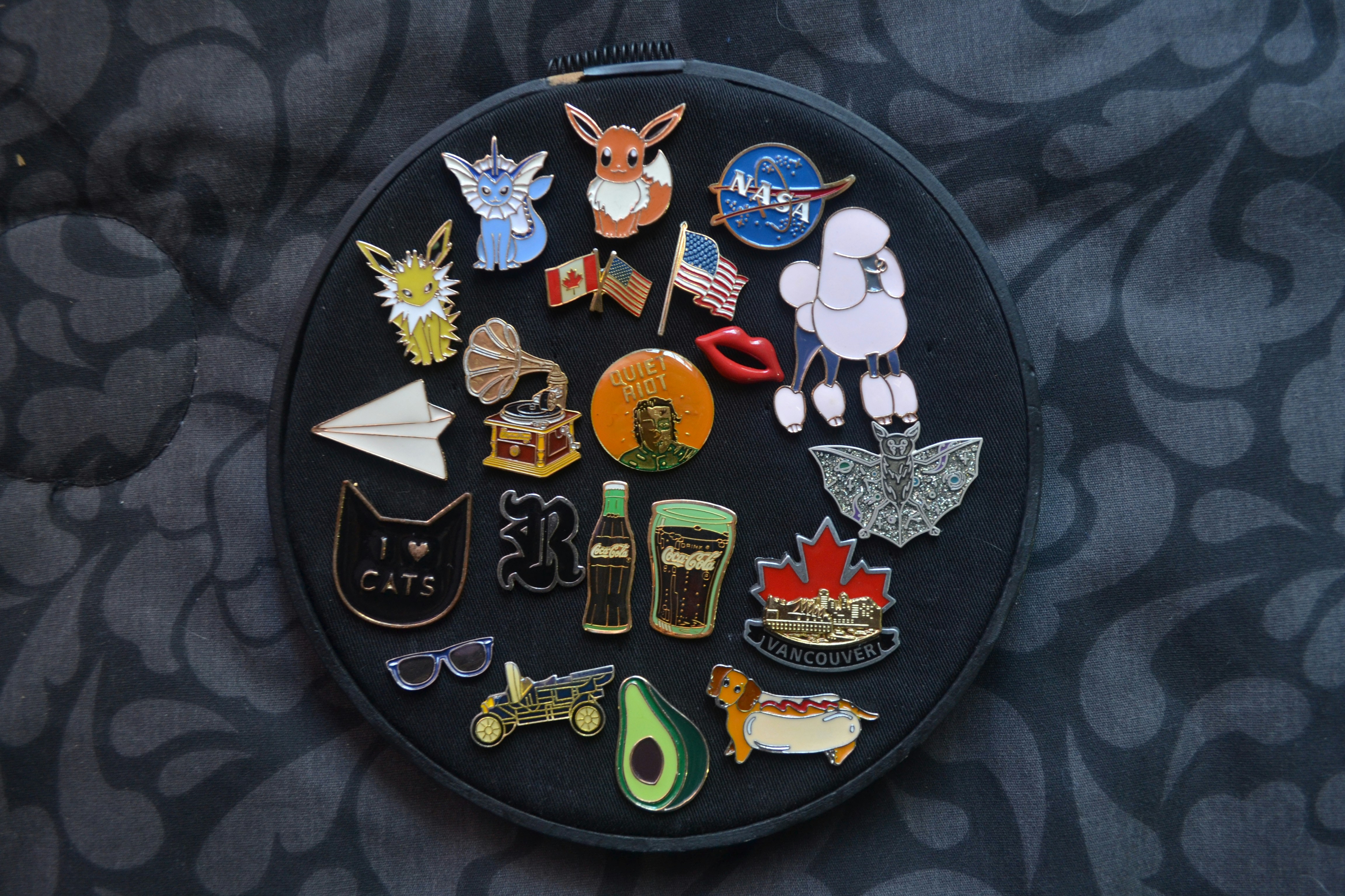 assorted enamel pins including flags, NASA, Pokemon and more.