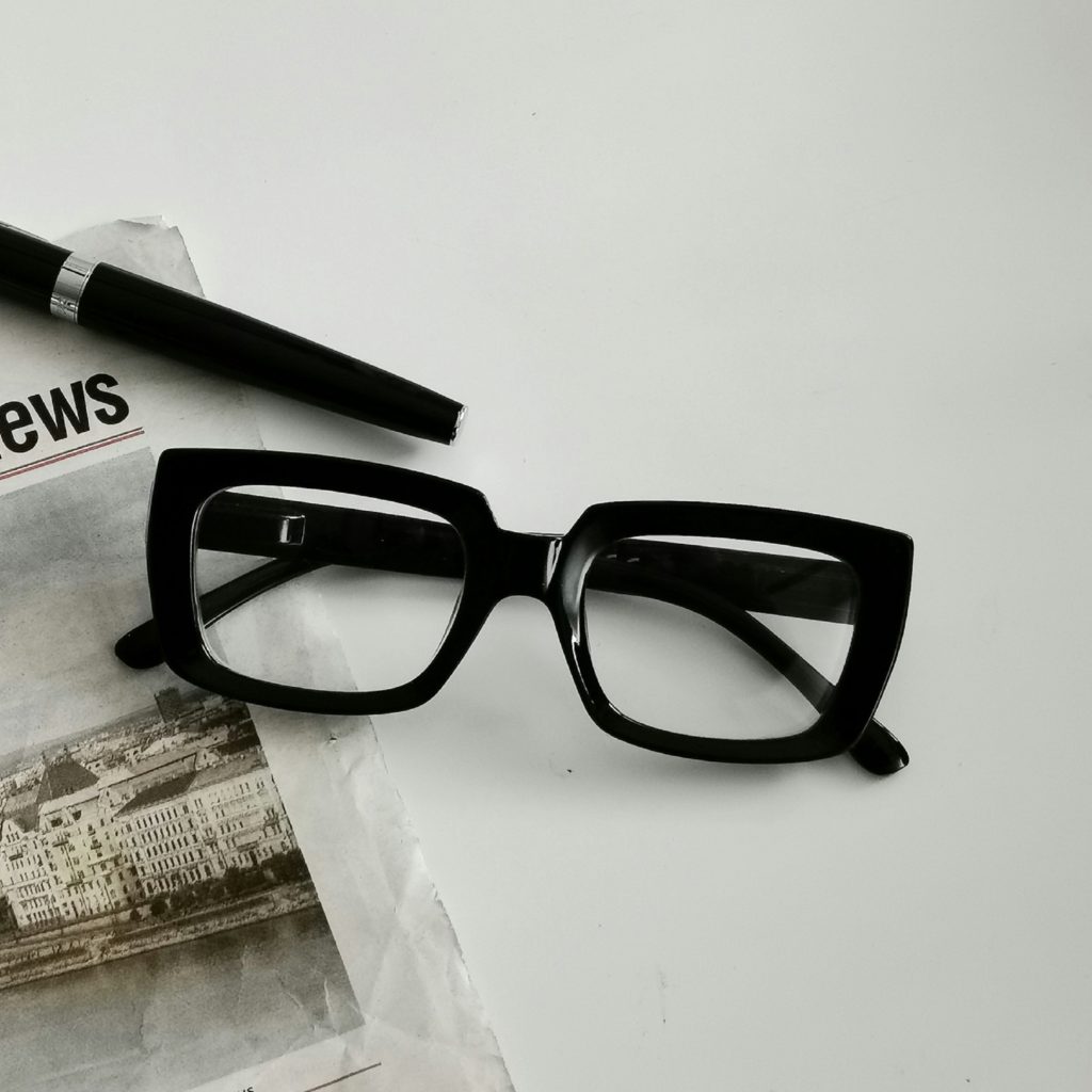 thick framed eyeglasses on top of a newspaper