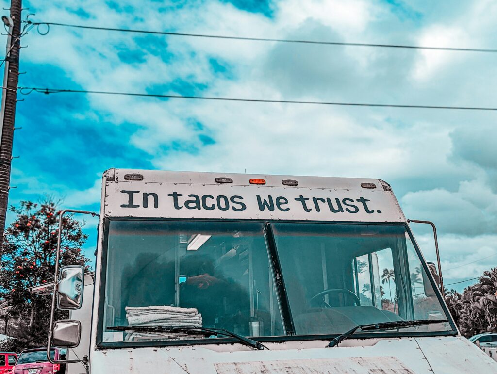 Taco truck with the phrase “In tacos we trust” written across the front of the truck
