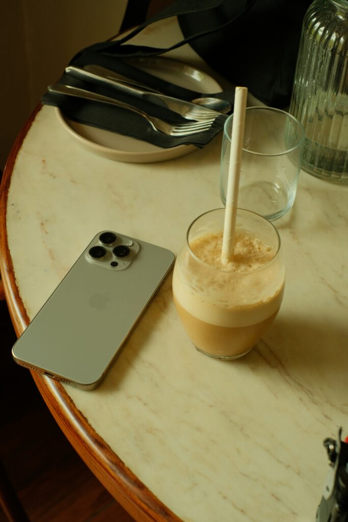 iPhone and a shake with a straw on a table next to one another